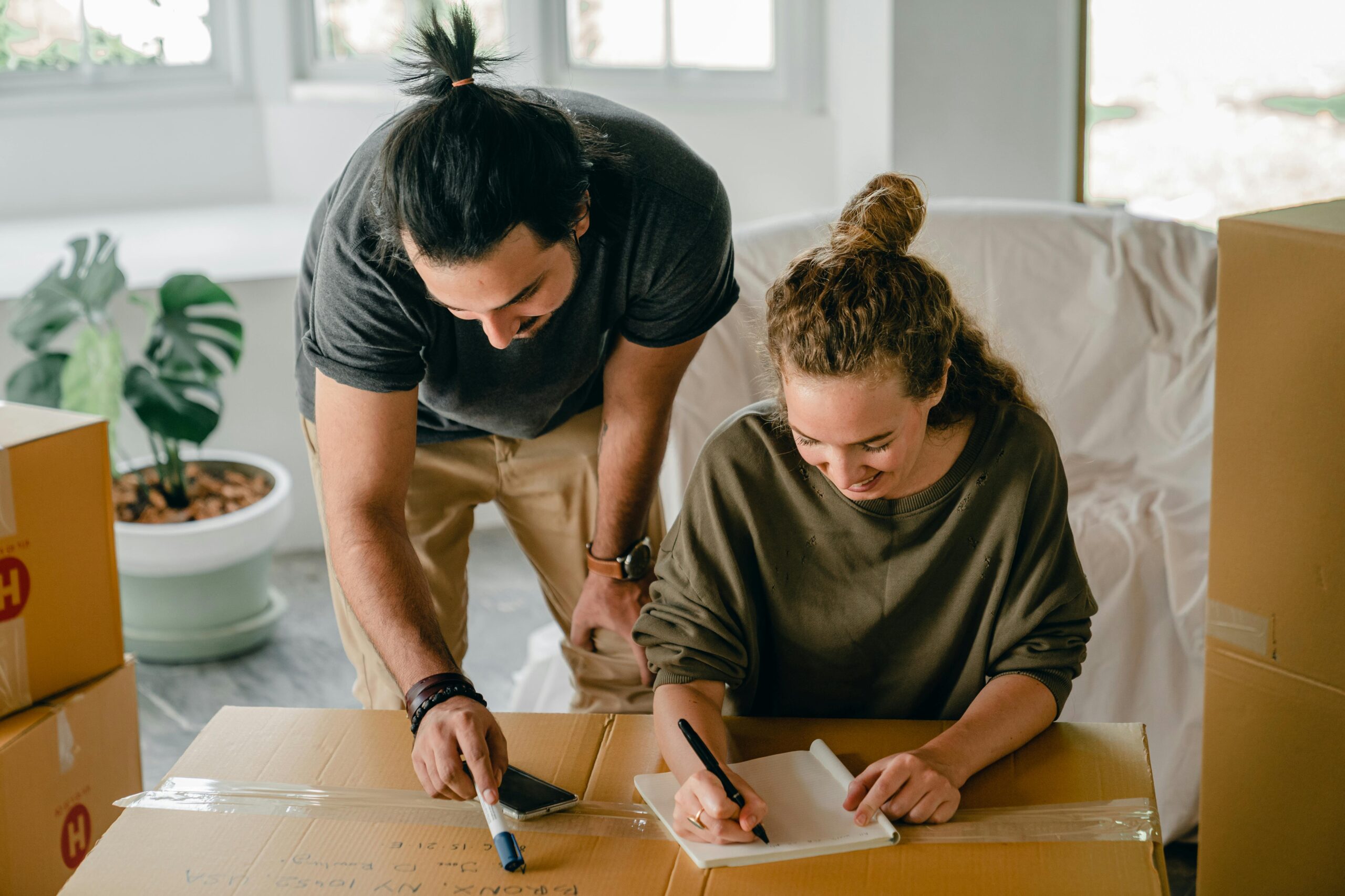 A cheerful couple organizing their move into a new home, surrounded by boxes and notes.