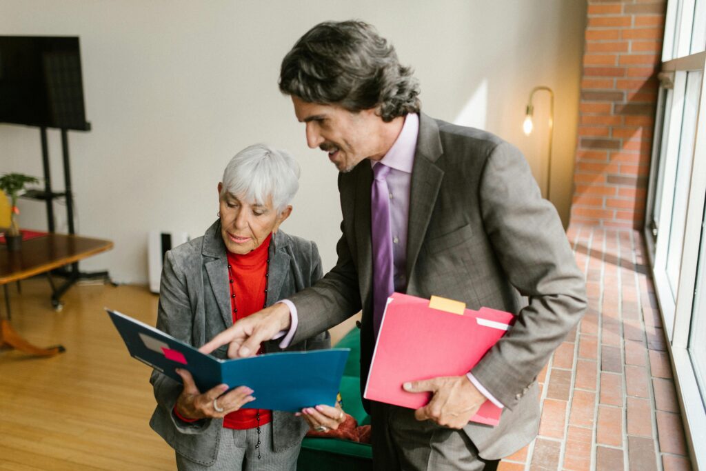 A senior businesswoman and businessman discussing documents in a modern office with natural light.