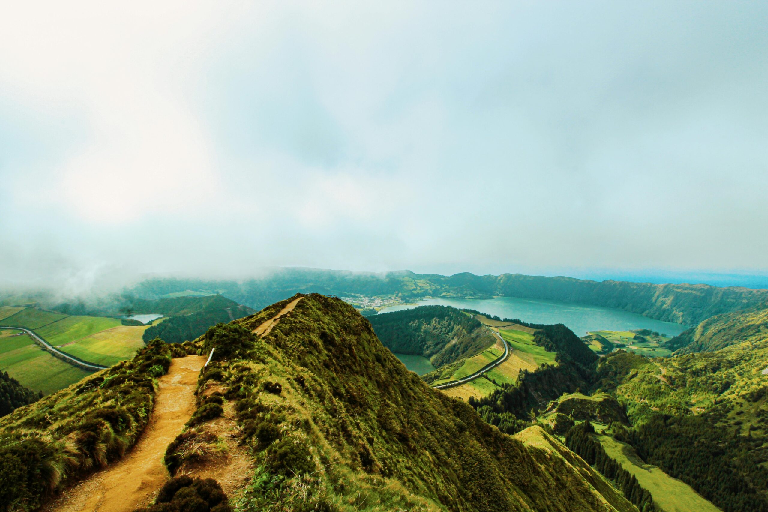 Explore the scenic beauty of the Azores with mountains, lush greenery, and a foggy lagoon view.