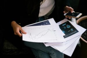 A person reviews stock market graphs on paper and smartphone for business insights.