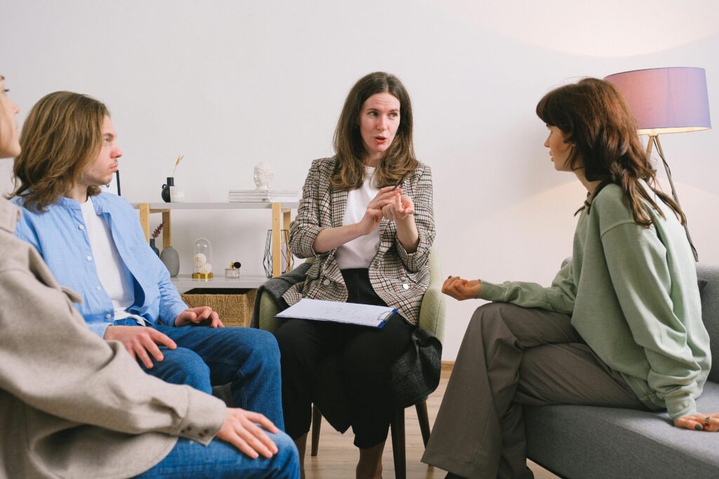 Female therapist during group session talking to female patients gathering in light cozy office