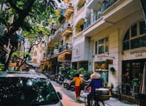 Vibrant street life in Hanoi with locals, cafes, and motorbikes on a sunny day.