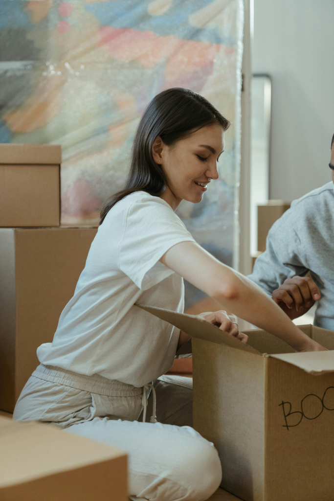 Woman unpacking in her new home with cardboard boxes around, symbolizing a fresh start.