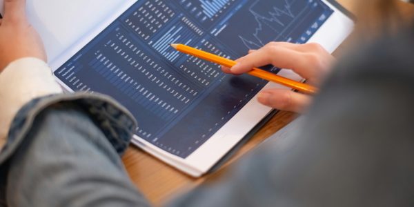 Focused image of hands analyzing business graphs and charts in a folder, highlighting data insights.