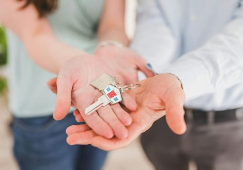Close-up of a couple holding keys, symbolizing homeownership and investment.